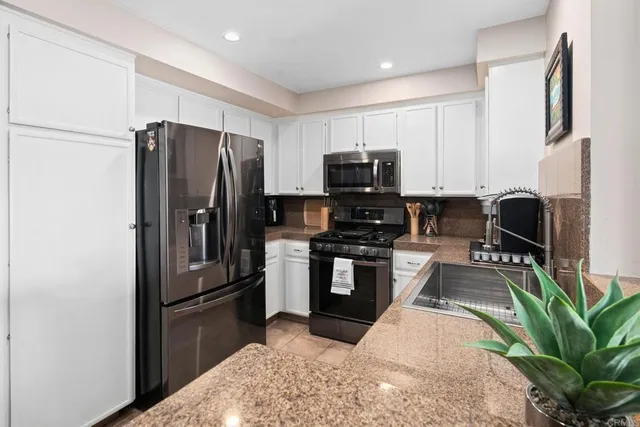 a kitchen with stainless steel appliances kitchen island granite countertop a refrigerator stove and sink