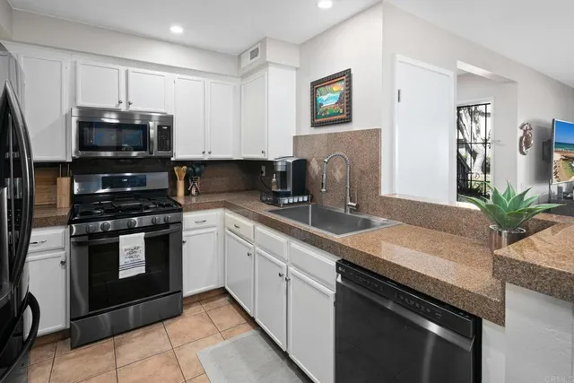 a kitchen with granite countertop white cabinets and stainless steel appliances