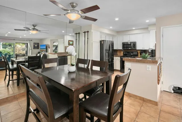a dining room with stainless steel appliances kitchen island granite countertop a dining table chairs and a refrigerator