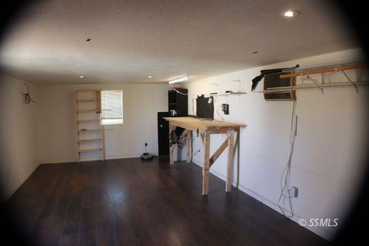 1241 South Mahan Street Ridgecrest, CA 93555 - Photo 21 of 28 an empty room with wooden floor and a kitchen