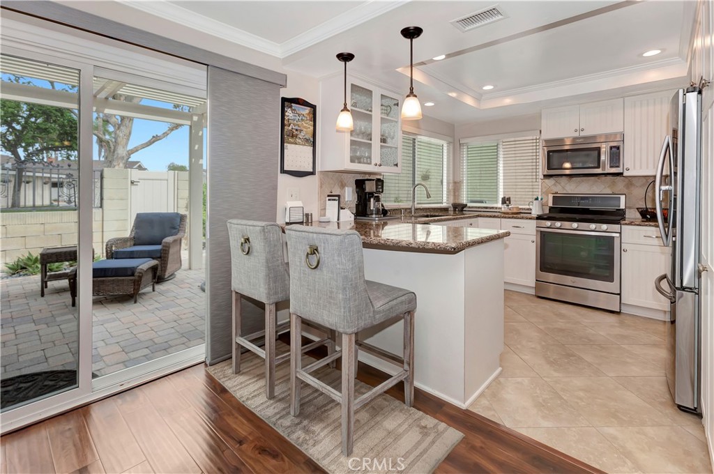 a kitchen with stainless steel appliances granite countertop a stove top oven a sink dishwasher a dining table and chairs with wooden floor