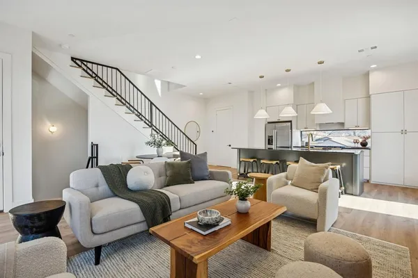 a living room with furniture kitchen view and a wooden floor