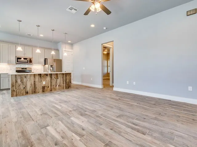 a view of a kitchen with kitchen island wooden floor center island and stainless steel appliances