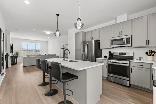 a kitchen with stainless steel appliances kitchen island a table chairs refrigerator and microwave