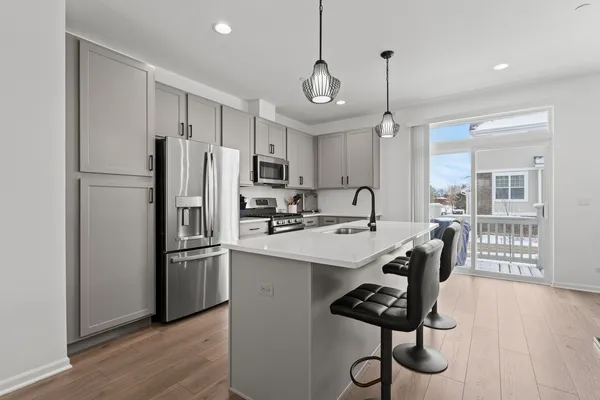 a kitchen with stainless steel appliances a refrigerator a sink a stove a dining table and chairs