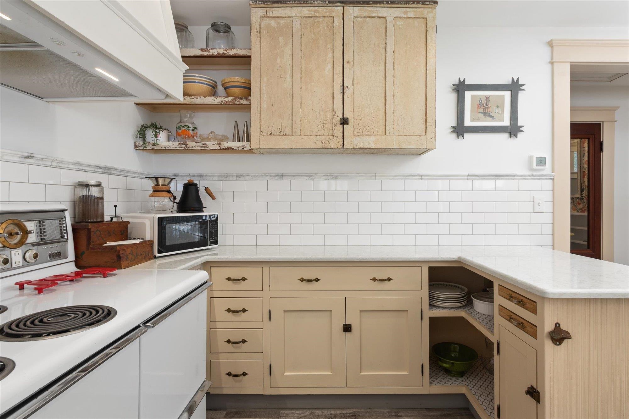 Kitchen with open shelves, white electric stove, premium range hood, a peninsula, and tasteful backsplash