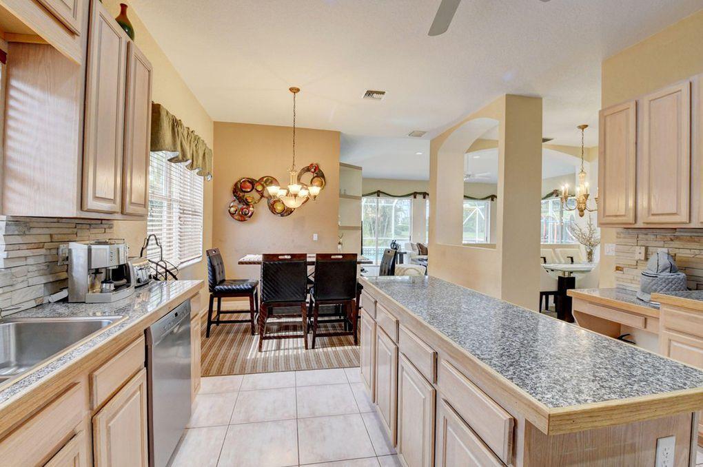 12320 Melrose Way Boca Raton, FL 33428 - Photo 14 of 34 a kitchen with stainless steel appliances granite countertop sink stove and cabinets