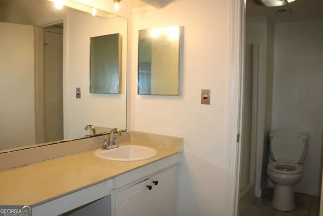 a bathroom with a granite countertop sink toilet and a mirror