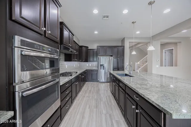 a kitchen with granite countertop stainless steel appliances and wooden floor
