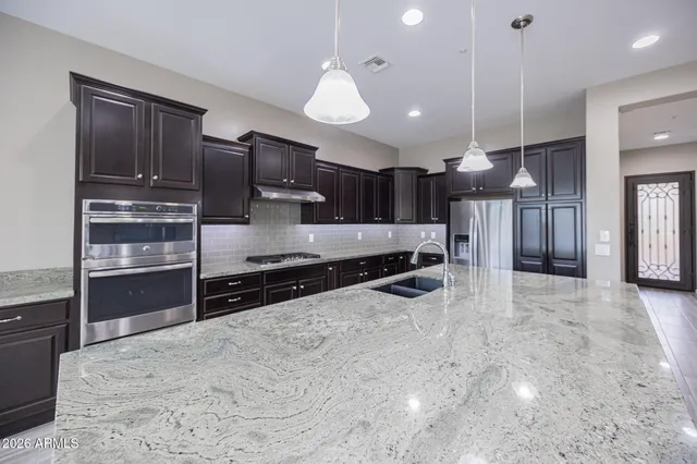 a kitchen with stainless steel appliances granite countertop a refrigerator a sink and a stove