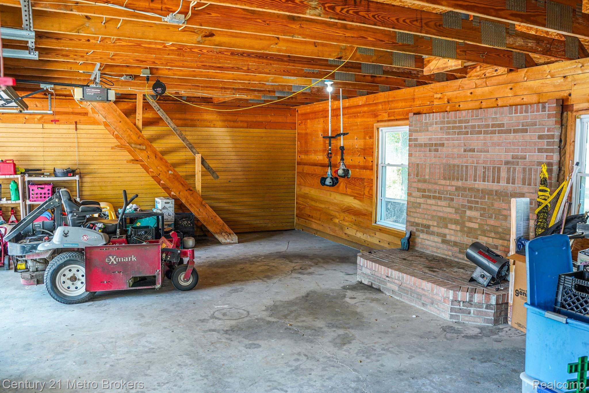 301 Field Road Clio, MI 48420 - Photo 31 of 32 Exposed wood beam ceiling, wood-paneled walls, brick fireplace hearth, two windows, and exposed wood staircase