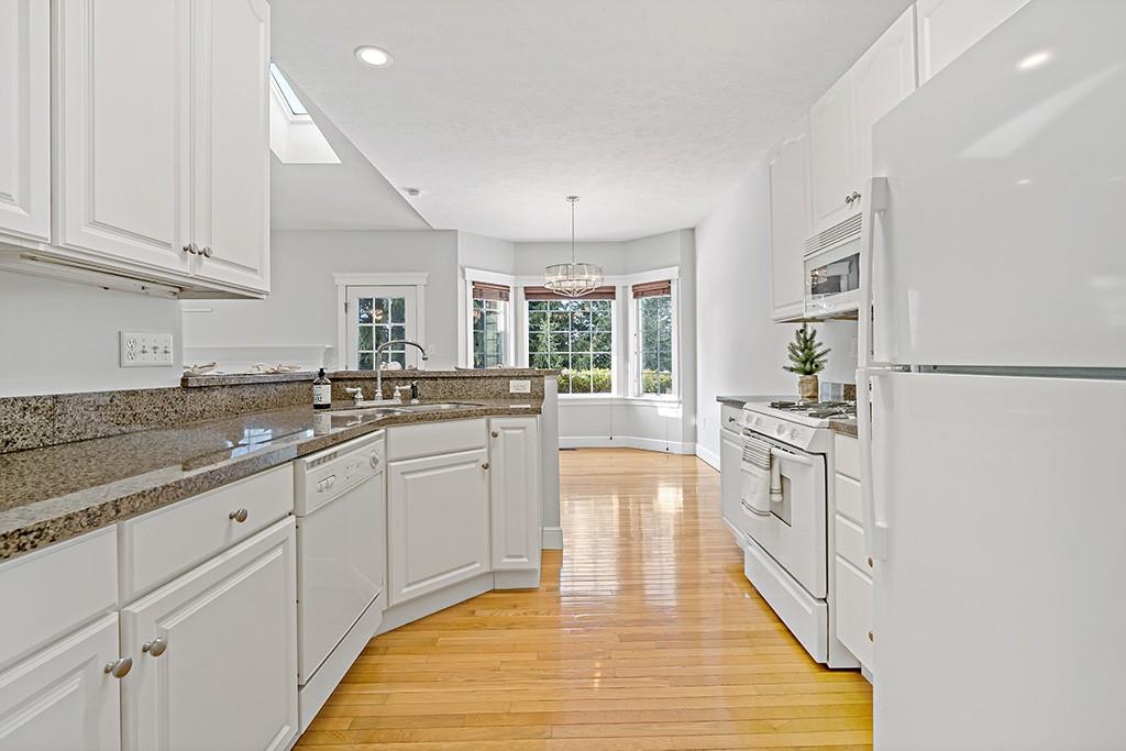 267 Berkeley Way Monroeville, PA 15146 - Photo 9 of 25 a large white kitchen with granite countertop a sink dishwasher a stove and white cabinets with wooden floor