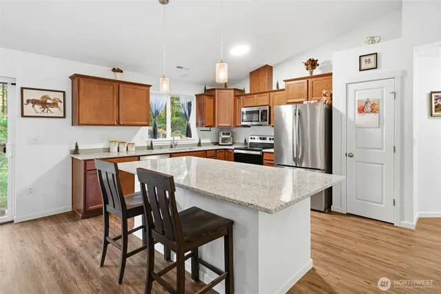 a kitchen with stainless steel appliances granite countertop a dining table chairs and refrigerator