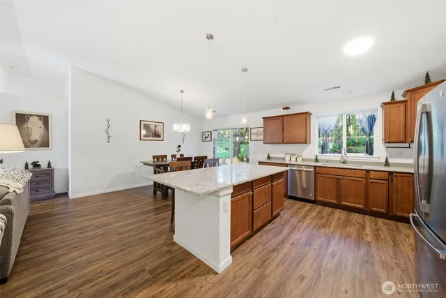 a large kitchen with stainless steel appliances a sink and a wooden floor