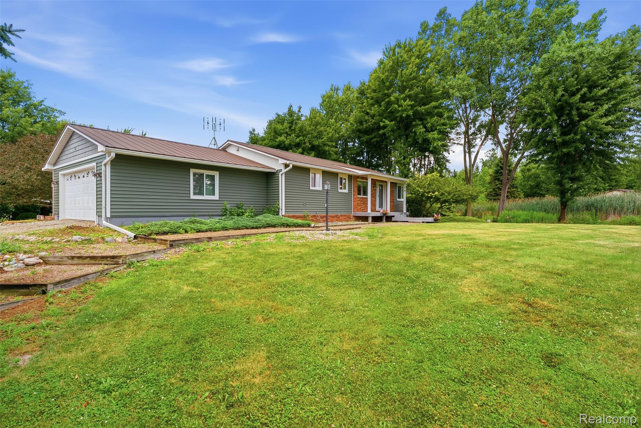 Ranch-style residence featuring green horizontal siding and a brown metal roof