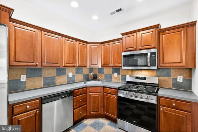 a kitchen with stainless steel appliances granite countertop a refrigerator and a stove top oven