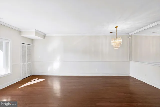 an empty room with wooden floor and window