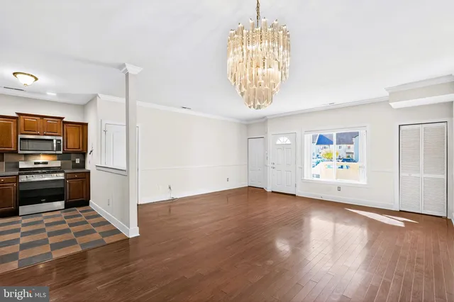 an empty room with wooden floor and kitchen view