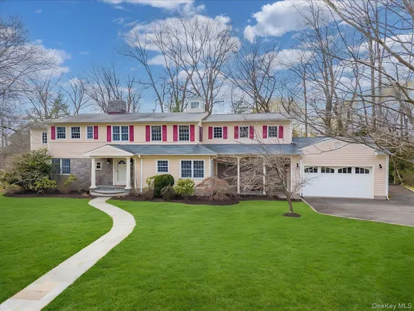 a view of a house next to a big yard and large trees