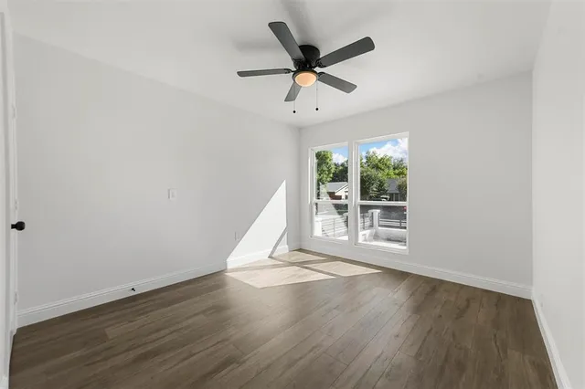 an empty room with wooden floor fan and windows