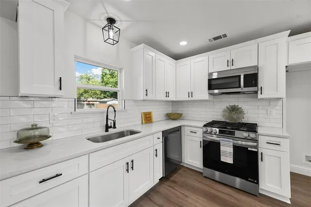 a kitchen with cabinets stainless steel appliances a sink and a window