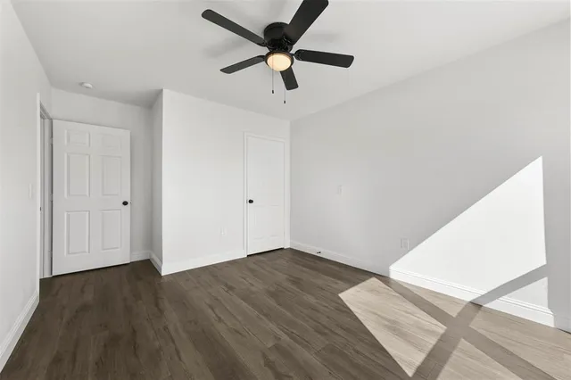 an empty room with wooden floor and a ceiling fan