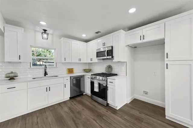 a kitchen with stainless steel appliances white cabinets a sink and a stove
