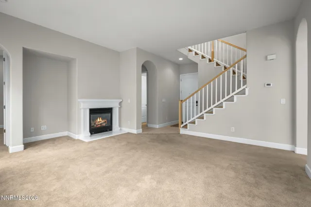 a view of an empty room with fireplace and stairs