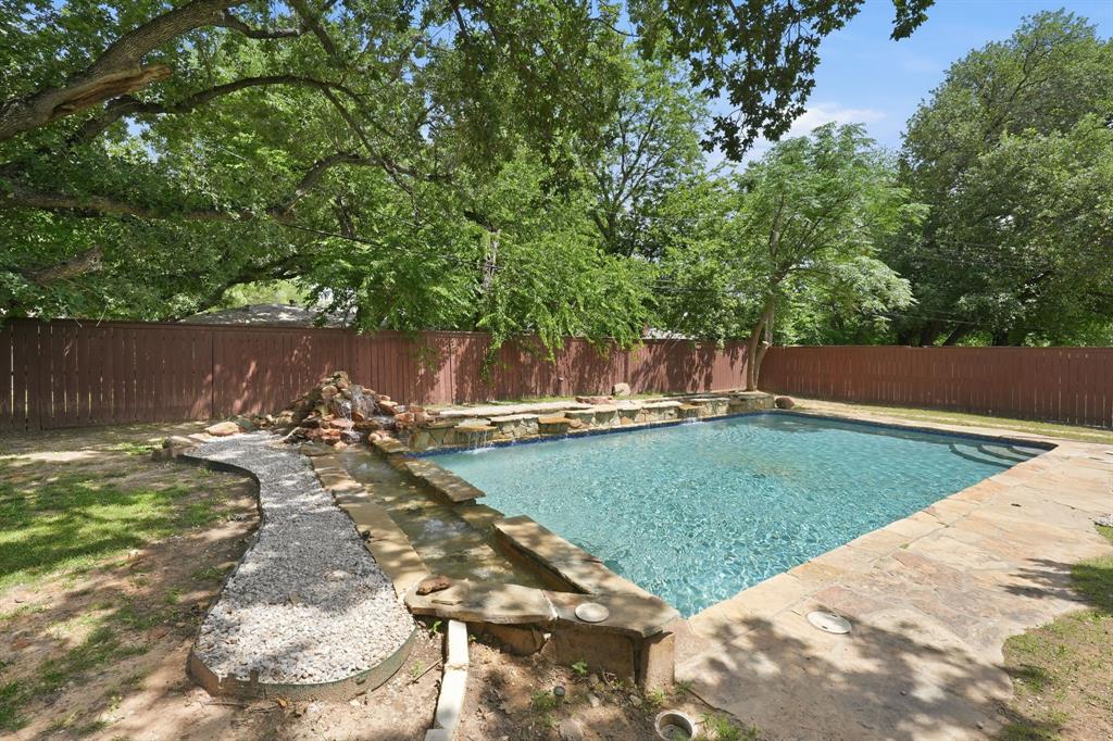 1108 Billie Ruth Lane Hurst, TX 76053 - Photo 26 of 27 Rectangular swimming pool featuring stone coping and a rock waterfall