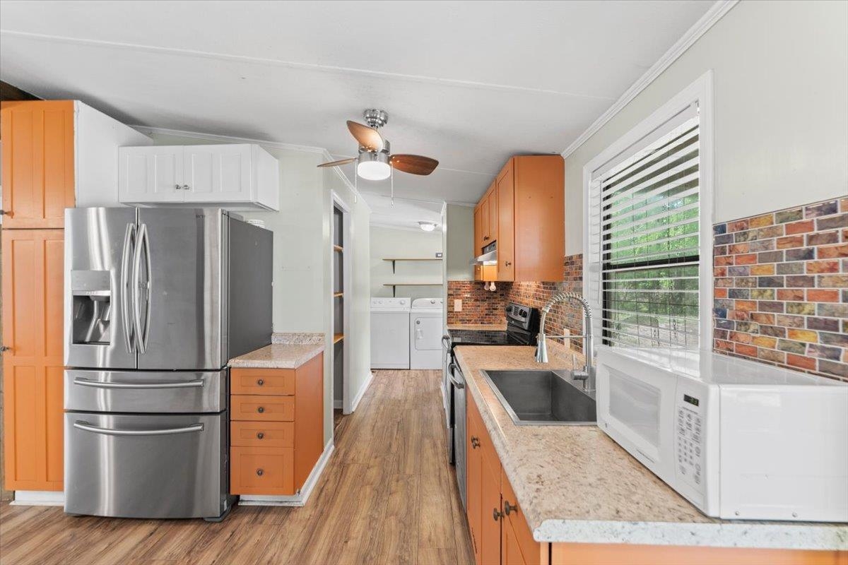 6860 Catlett Road St. Augustine, FL 32095 - Photo 10 of 36 Kitchen featuring stainless steel fridge, white microwave, light wood finished floors, washer and clothes dryer, and crown molding