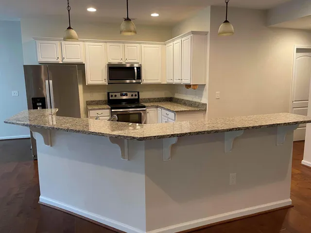 a kitchen with stainless steel appliances a refrigerator a stove a sink and white cabinets