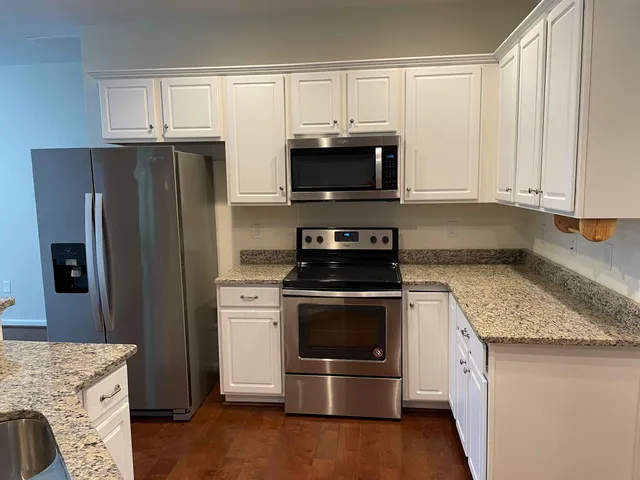 a kitchen with granite countertop a refrigerator stove and microwave