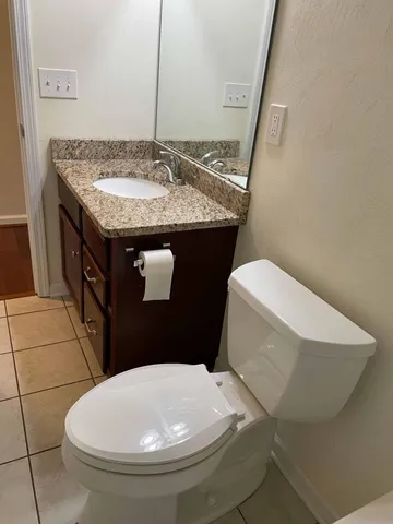 a bathroom with a granite countertop toilet and a sink