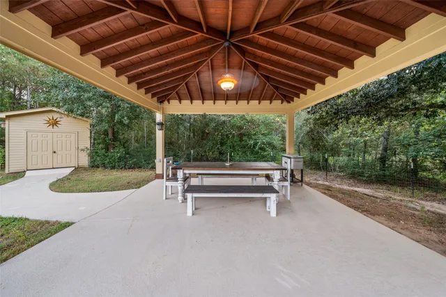 a view of patio with a table and chairs under an umbrella with a small yard