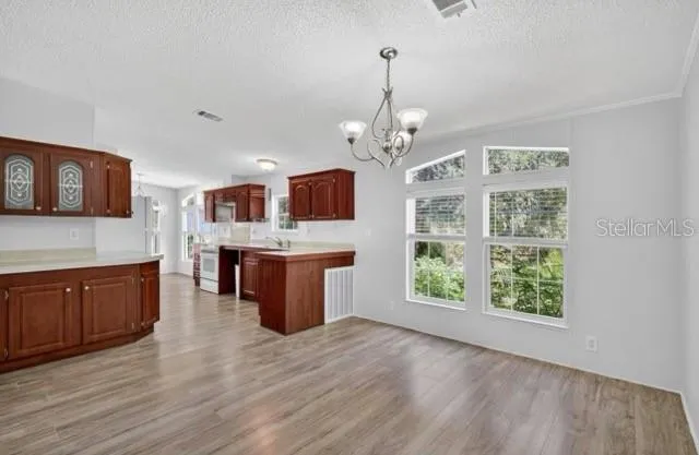 a large kitchen with stainless steel appliances granite countertop a refrigerator a sink dishwasher a dining table and chairs with wooden floor