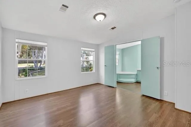 an empty room with wooden floor and windows