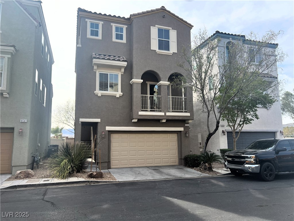 View of front of house with a balcony, stucco siding, an attached garage, driveway, and a tile roof