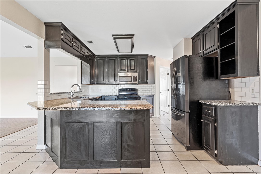 1312 North Rock Creek Road Waco, TX 76708 - Photo 8 of 46 a kitchen with stainless steel appliances granite countertop a stove a refrigerator and a sink