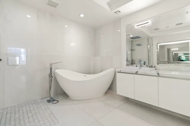 a bathroom with a bathtub a sink a mirror and a shower