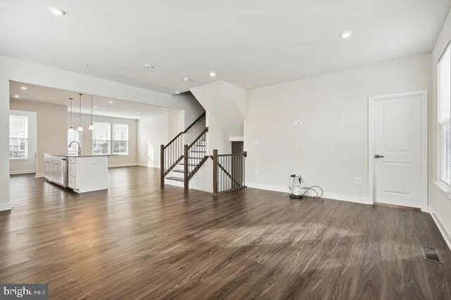 a view of empty room with wooden floor and a kitchen