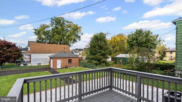 a view of a white house with a large tree and wooden fence