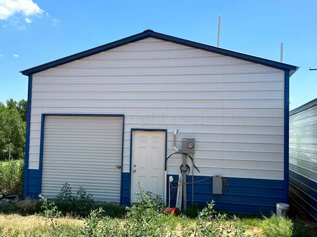 a backyard of a house with plants and large tree