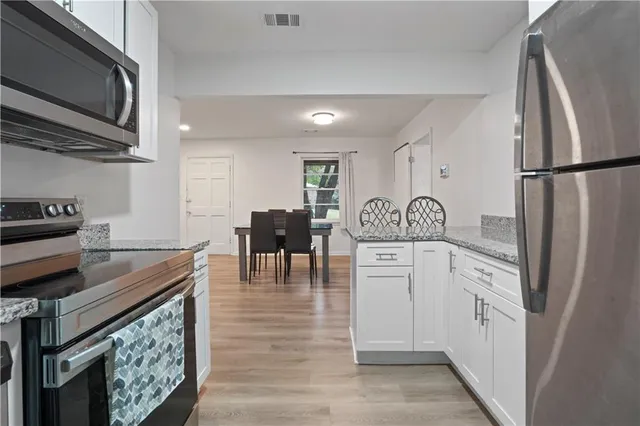 a kitchen with white cabinets and stainless steel appliances
