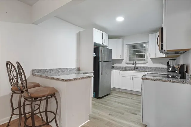 a kitchen with granite countertop white cabinets and stainless steel appliances