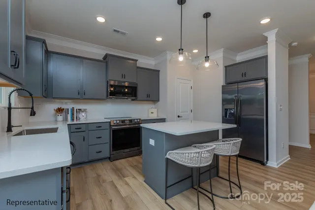 a kitchen with kitchen island granite countertop a sink a counter space appliances and cabinets