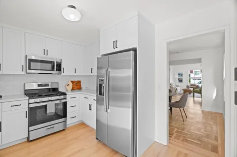 a kitchen with cabinets stainless steel appliances and wooden floor