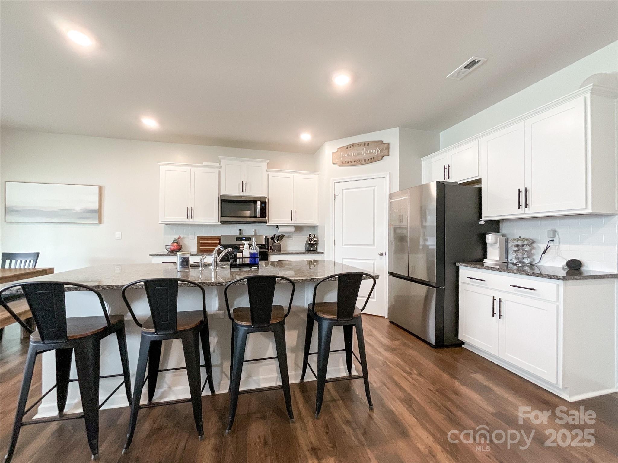 2159 Vanderlyn Street Monroe, NC 28112 - Photo 11 of 44 a kitchen with stainless steel appliances granite countertop a dining table chairs refrigerator microwave and cabinets