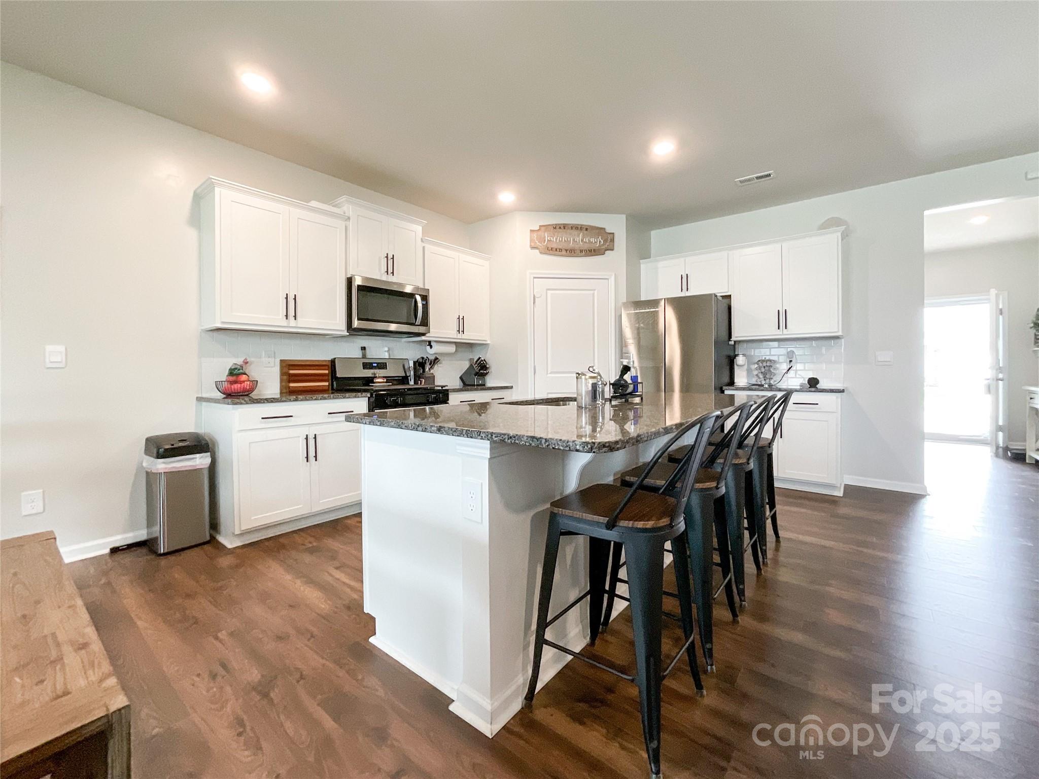2159 Vanderlyn Street Monroe, NC 28112 - Photo 12 of 44 a kitchen with a table chairs a sink dishwasher a refrigerator and cabinets with wooden floor