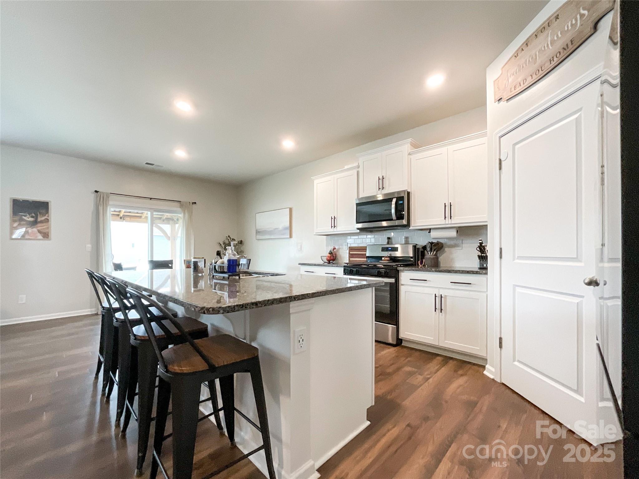 2159 Vanderlyn Street Monroe, NC 28112 - Photo 10 of 44 a kitchen with kitchen island granite countertop wooden floors and wooden cabinets