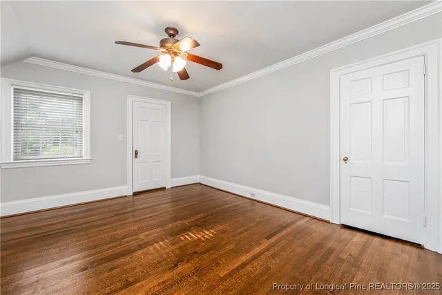 a view of an empty room with wooden floor and a ceiling fan